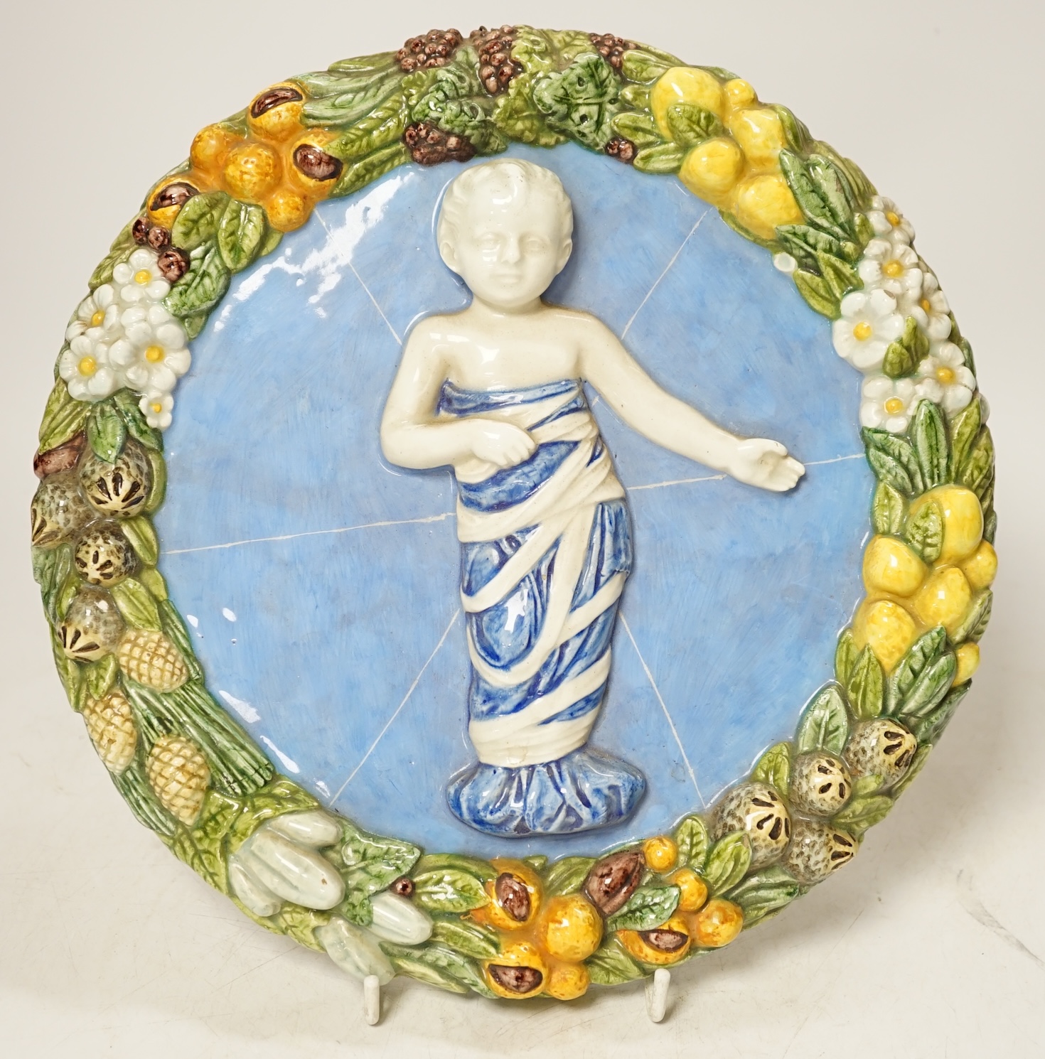 A Della Robbia style circular maiolica plaque, 26cm diameter. Condition - good.